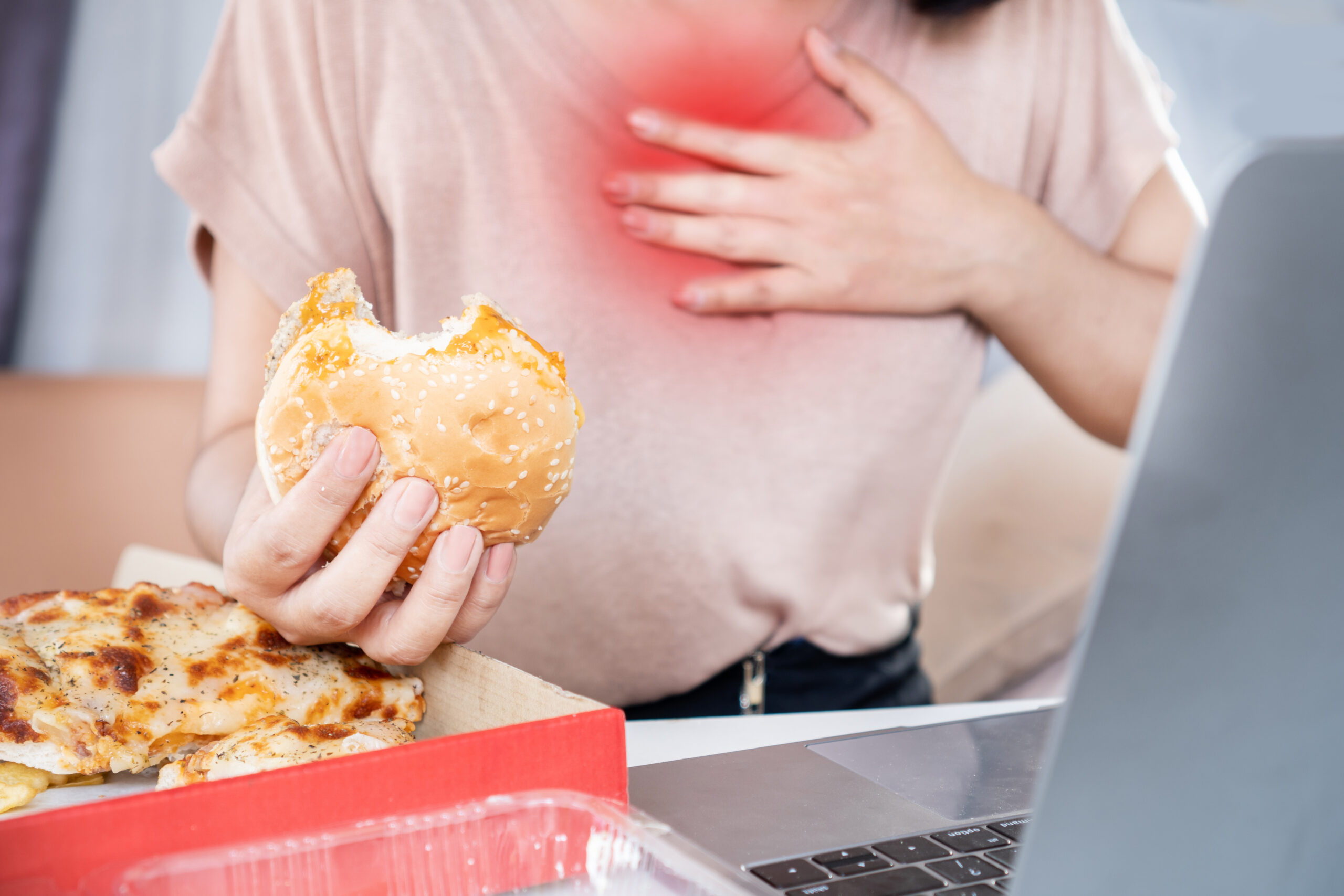 woman suffering from acid reflux , heartburn after over eating junk food, pizza and burger